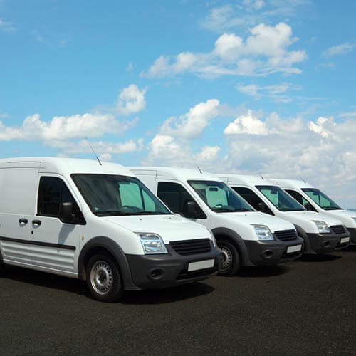 Image shows four white transit vans in a row